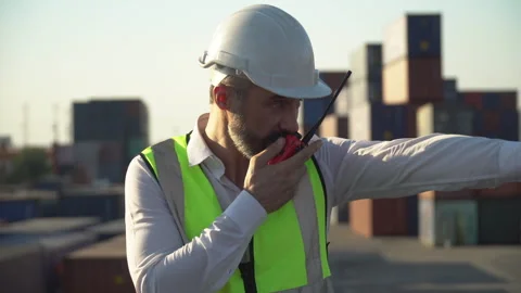 Old foreman busy talking on the walkie-talkie control loading Containers bo.. Stock Footage 248363883