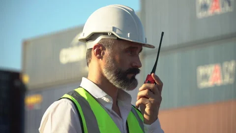 Old foreman talking on the walkie-talkie control loading Containers box at .. Stock Footage 248363291