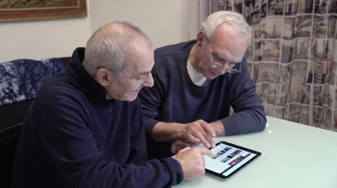 Old friends sit at the table using tablet Stock Footage 63419734