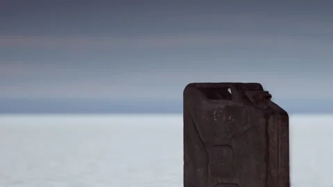 Old fuel can on a flat surface near water at sunset Stock Footage 344137260