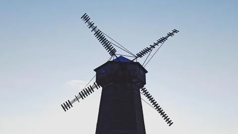 An old but functional windmill in a rural area with a blue sky. 库存照片