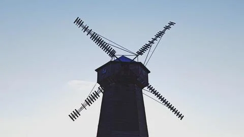 An old but functional windmill in a rural area with a blue sky. 写真素材