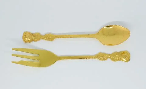 Old gilded spoon and fork lie next each other Stock Photos