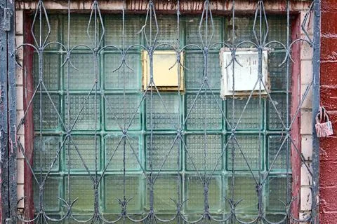 Old glass block window protected by rusty metal security bars in urban building Stock Photos