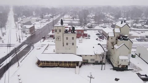 Old grain elevator facility and small township during snowfall, aerial Stock Footage 247684212