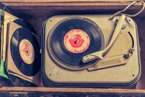 Old gramophone and stack of vinyl in an old suitcase Stock Photos