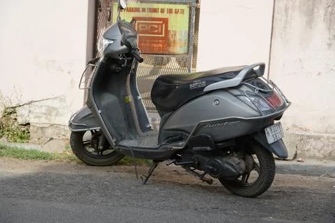 An old gray colored TVS Jupiter scooter parked outside a house. Two-wheeler i Фото