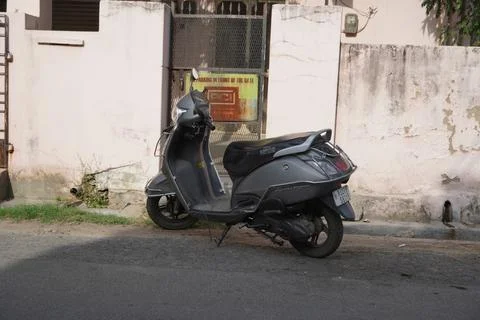 An old gray colored TVS Jupiter scooter parked outside a house. Two-wheeler i Stock Photos