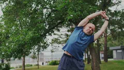 Old Gray-haired Man Makes Fitness or Gymnast Outdoor. Hue Rotate his back and Stock Footage 148465566