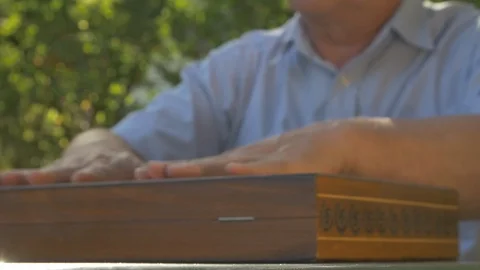 Old gray-haired man opens the chess game outside in the garden at the table and Stock Footage 118613597