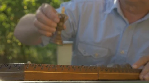 Old gray-haired man opens the chess game outside in the garden at the table and Stock Footage 118615971