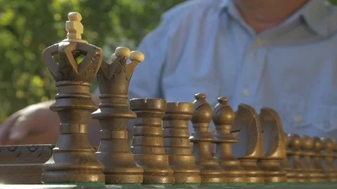 Old gray-haired man prepares the chess game outside in the garden at the table Stock Footage 118616475