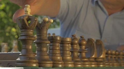 Old gray-haired man prepares the chess game outside in the garden at the table Stock Footage 118618109