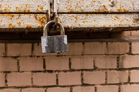 Old gray padlock security lock on a metal rusty box background and a brick Stock Photos