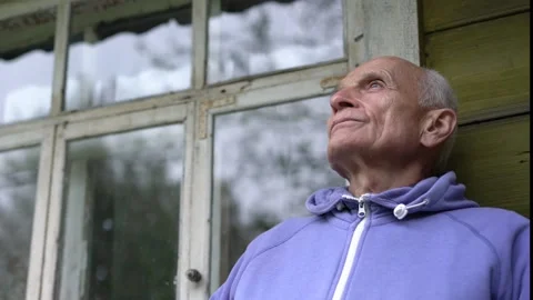 Old grayhaired elder man sitting on wooden bench and thinking window background Stock Footage 143095888