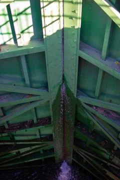 Old green bridge structure with visible details and water flow underneath Stock Photos