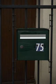 An old green postbox with the number 75, which hangs on the fence at the en.. Stock Photos