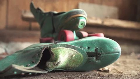 Old green roller skates with red wheels in shed / Focus on side skate Stockbeeldmateriaal 130885963