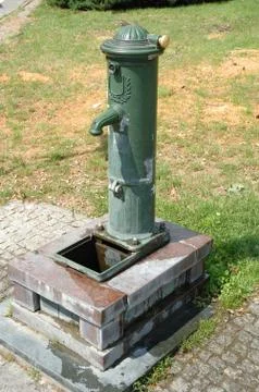 Old, green water pump standing in park Stock Photos