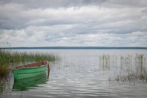 An old green wooden fisherman's boat stands on the shore of the lake Stock Photos