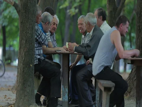 Old grey-headed men are playing cards in the park and smoking cigarettes. Stock Footage 73539245