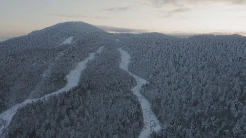 Old grown in ski trails wind down from the top of a snow crusted mountain Video stock 122690993