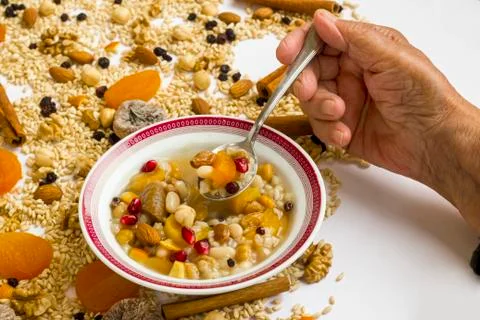 An old hand eats Turkish Dish Ashura from white bowl Stock Photos