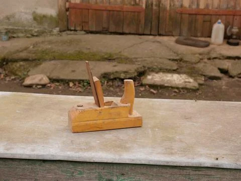 Old hand plane lying on stone slab in yard as traditional woodworking tool Stock Photos