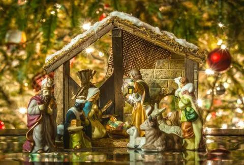 Old handmade nativity scene in front of a christmas tree Stock Photos