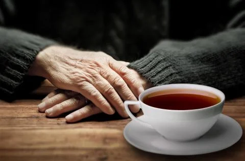 Old hands and a cup of tea with dramatic lighting Stock Photos