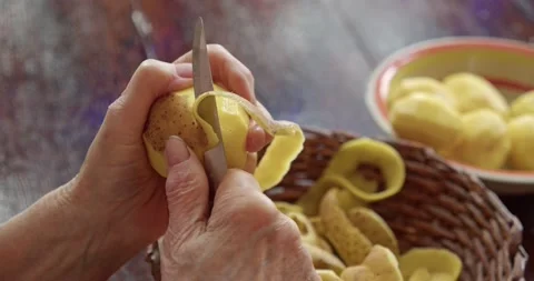 Old hands peel potatoes. The work of elderly people forced to take care of Stock Footage 172527512