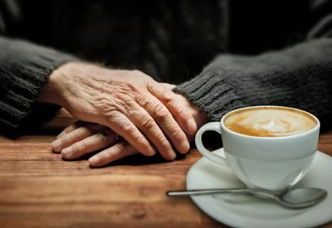 Old handsand cup of cappuccino in dramatic lighting Stock Photos