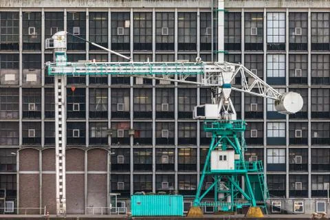 Old harbor crane in front of an ancient factory Stock Photos