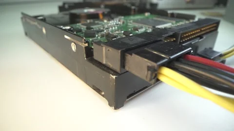 Old hard drive disk HDD with connected power cable in lab. White table. Macro Video stock 141584679