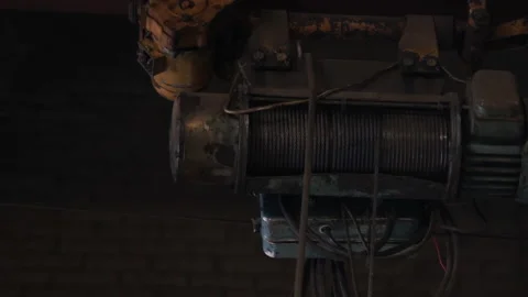Old hoist with rotating roller pays out metal cable at plant Stock Footage 101046063