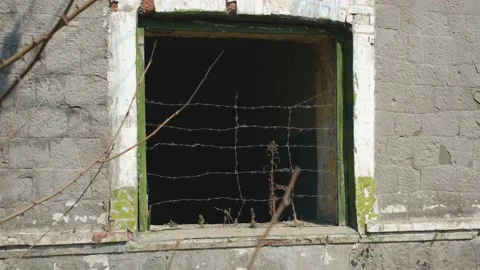 An old house with a window behind barbed wire Stock Footage 194068523