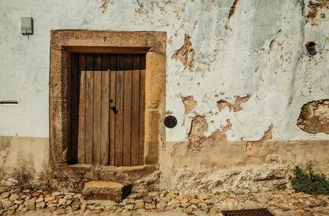 Old house with worn plaster wall and wooden door Stock Photos