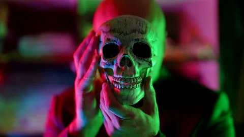 Old human skull in hands of strange man in neon lights, mysterious portrait Stock Footage 166098763