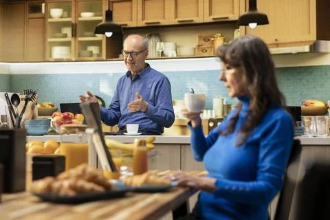 Old husband using computer for web video call in his kitchen apartment Stock Photos