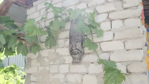 Old Inca or other empire mask hangs on brick concrete white wall. Scary face of Stock Footage 137613076