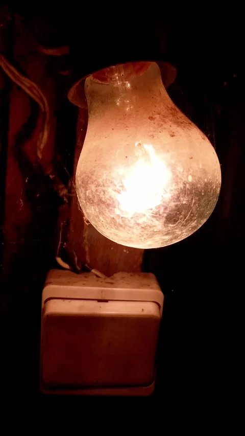 Old Incandescent Light Bulb Glowing Beside Dusty Switch in Dark Room Stock Footage 339003835