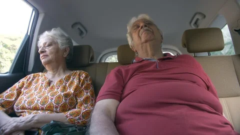 Old Indian couple sleeping in the back seat of a moving car - senior lifestyl... Stock Footage 124575890
