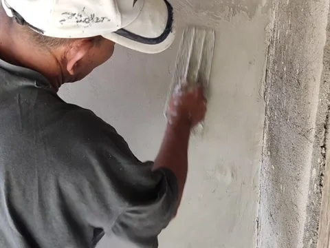 An old Indonesian builder is plastering a wall using traditional tool Stock Footage 197707061