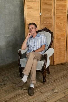 An old intelligent man having a rest on a armchair Stock Photos