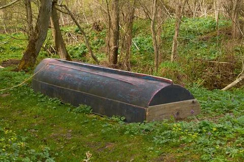 An old inverted plastic boat is lying on the grass Stock Photos
