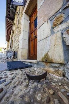 Old iron boot scraper by rustic stone house entrance with cobblestone pavemen Stock Photos