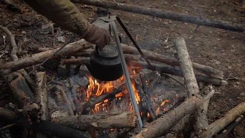 An old iron kettle is boiling on a tripod for a fire Stock Footage 113826813