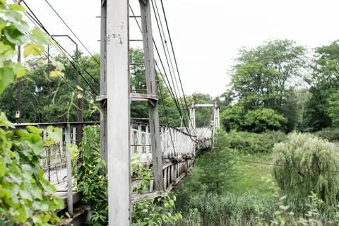 Old iron non-functioning suspension bridge over a dried river side view. On the Stock Photos