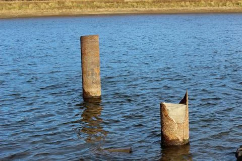 Old iron pipes driven into the river Stock Photos