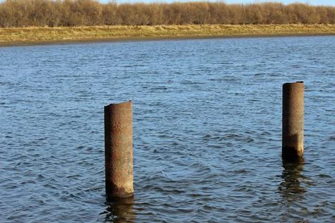 Old iron pipes driven into the river Stock Photos